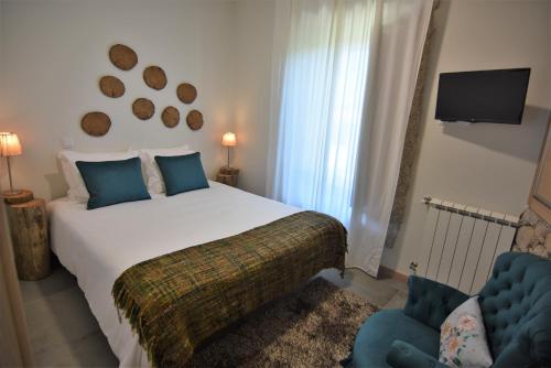 1 dormitorio con 1 cama blanca y 1 silla azul en Quinchoso dos Bentos, en Vila Pouca de Aguiar