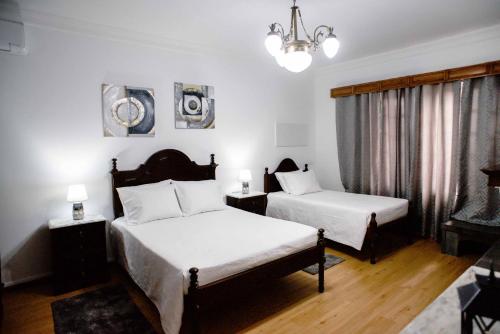 a bedroom with two beds and a chandelier at Vivenda Glorizé in Água de Alto