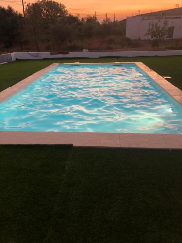 a large swimming pool with a sunset in the background at Casa da Azenha Castellvm in Alcabideque