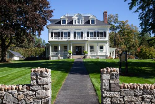 a large white house with a stone wall at Inns of Aurora Resort & Spa in Aurora
