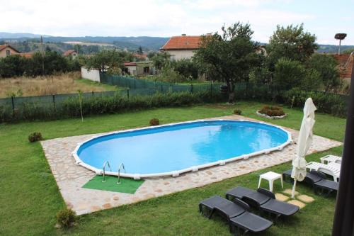 a large swimming pool in a yard with lounge chairs at Къщи за гости Ореха in Samokov