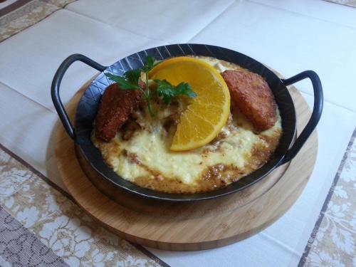 a bowl of omelet with sausage and an orange slice at Hotel-Café-Burg Stahleck in Bacharach
