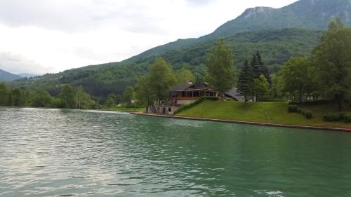 a house on the side of a river with mountains at Apartmani Šarović in Tjentište