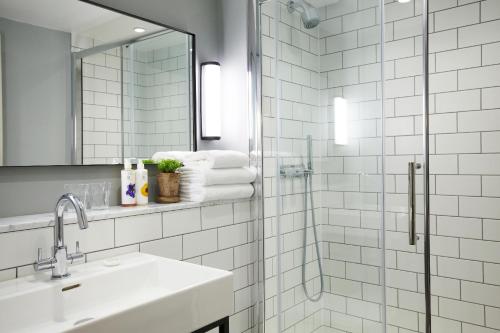 a bathroom with a shower, sink, and mirror at Lime Tree Hotel in London