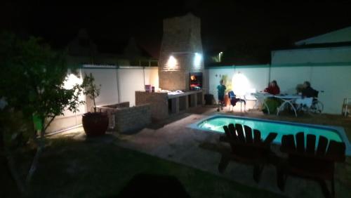 a swimming pool at night with people sitting around a table at Welterusten Guesthouse in Strand