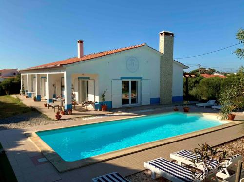 a villa with a swimming pool in front of a house at Endless Summer Surf House in Aljezur