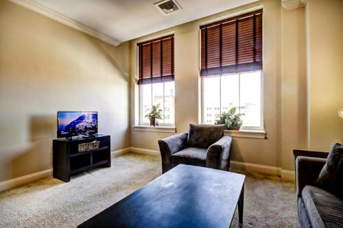 a living room with a tv and two chairs and a table at Harbor apartments Free indoor Parking in Baltimore