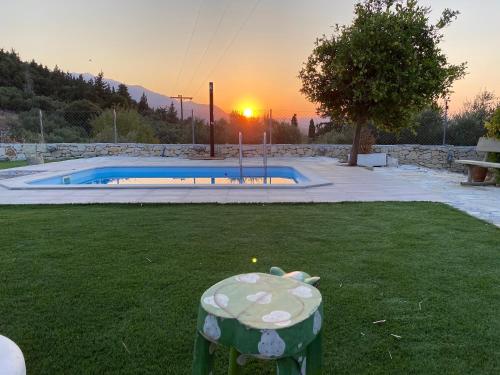 a garden with a table in the grass with a pool at Old stone villa in Apokoronas Villa Nostalgia Kreta in Fílippos