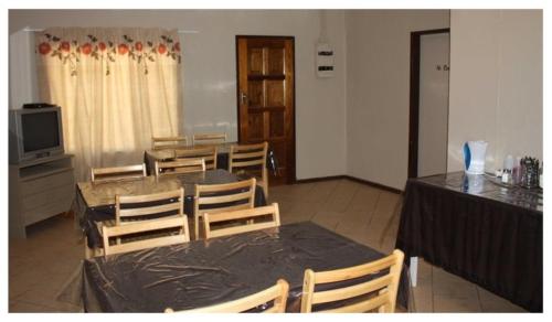 una sala da pranzo con tavolo, sedie e TV di Abuelita Guesthouse - Room 1 a Lephalale