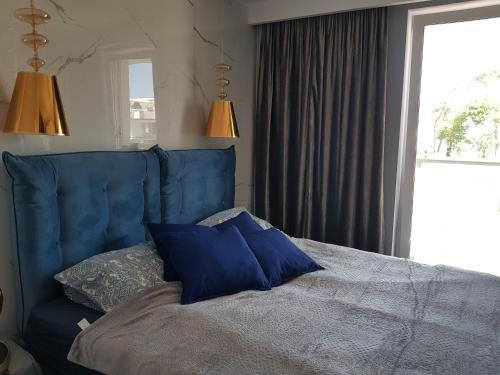 レバルにあるWhite apartaments Rewalのベッドルーム(青い枕付きの青いベッド1台付)