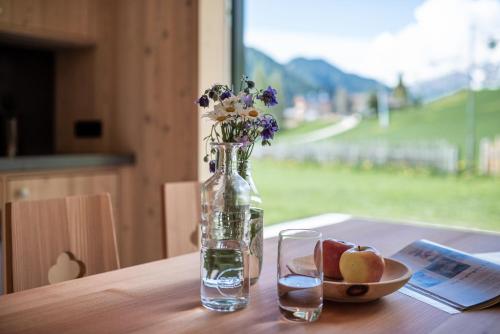 un vaso con fiori e un cesto di frutta su un tavolo di Larix Lodge a La Villa