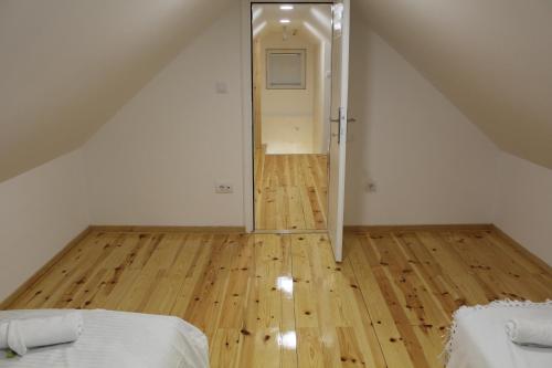 an attic room with a bed and a wooden floor at Kucica u Šumi in Užice