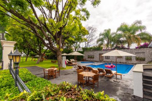 a patio with tables and chairs next to a pool at Hotel Flamingo Inn in Querétaro