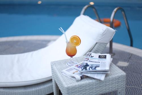 a drink on a table with a newspaper and a magazine at Capitol Hotel Jumeirah Dubai in Dubai