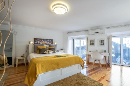 um quarto branco com uma cama com um cobertor amarelo em Lisbon City Center Baixa em Lisboa