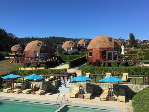 a resort with a pool and some tables and umbrellas at Pichilemu Domos in Pichilemu