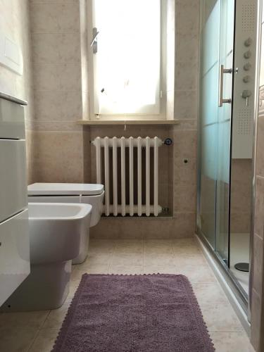 a bathroom with a toilet and a window and a radiator at Appartamento Via Rieti in Senigallia