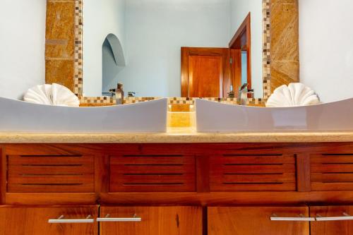 a bathroom with a large sink with two mirrors at Modern, Immaculate Unit in Flamingo with Spectacular Ocean Views in Playa Flamingo