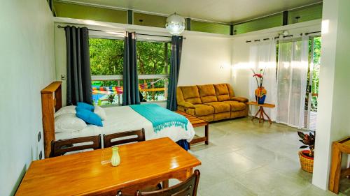 a bedroom with a bed and a table and a couch at Agutipaca Bungalows in Bagaces