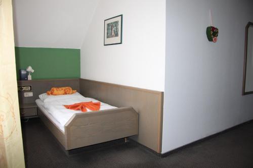 a bedroom with a bed with an orange robe on it at Hotel am Schloss Neuenstein in Neuenstein