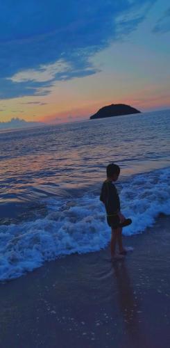 a young child standing on the beach at sunset at Bungalows Maria Teresa in Rincon de Guayabitos