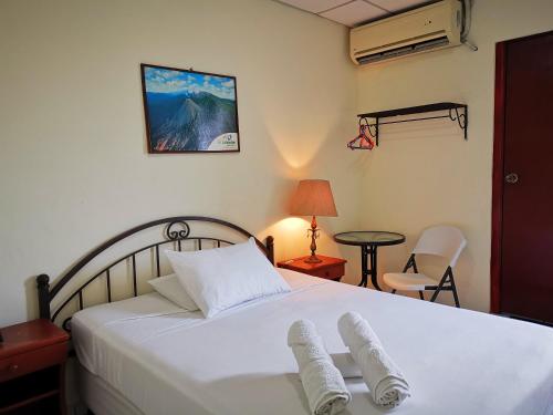 1 dormitorio con 1 cama blanca y 2 toallas en Hotel Armonía Hostal, en San Salvador