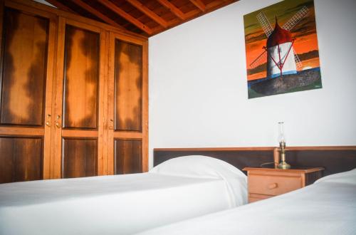 a bedroom with two beds and a painting on the wall at Quinta dos Frutos in Santa Cruz da Graciosa