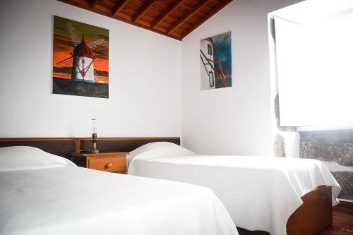 two beds in a room with a lighthouse picture on the wall at Quinta dos Frutos in Santa Cruz da Graciosa