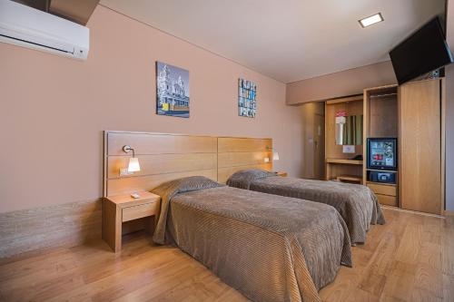 a hotel room with two beds and a flat screen tv at Hotel Botanico in Lisbon