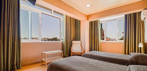 a hotel room with two beds and two windows at Hotel Botanico in Lisbon