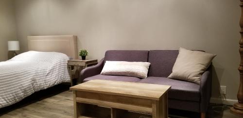 a living room with a purple couch next to a bed at Remodeled Cottage in Berkeley/Oakland Rockridge in Oakland