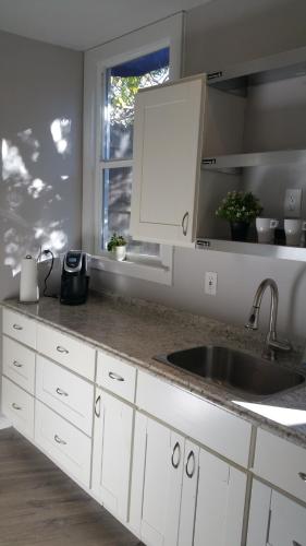 奧克蘭的住宿－Remodeled Cottage in Berkeley/Oakland Rockridge，厨房配有白色橱柜、水槽和窗户。