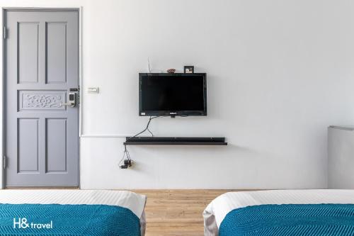 a room with a tv on the wall next to a door at Sleepier Multi-Minsu Tainan in Tainan