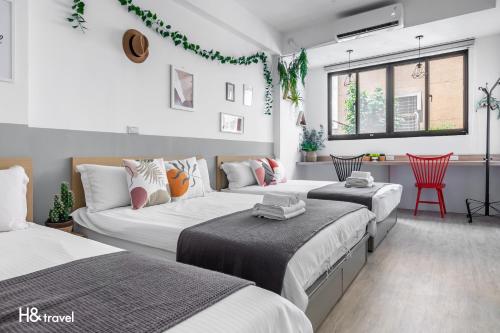 a bedroom with two beds and a red chair at Sleepier Multi-Minsu Tainan in Tainan