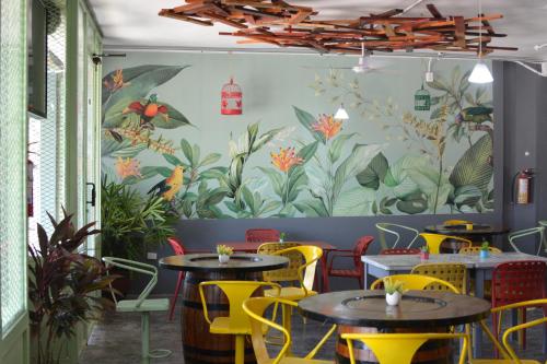 a restaurant with tables and chairs and a mural of plants at La Maja Suites in Villahermosa
