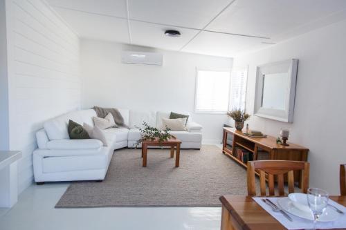 a white living room with a couch and a table at The Rested Guest 3 Bedroom Cottage West Wyalong in West Wyalong