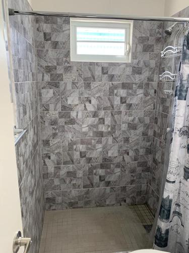 a bathroom with a shower with a stone wall at Mar Bonita Beach Apartment in Isabela