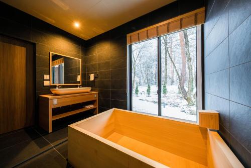 a bathroom with a large tub and a window at Gravity by The Hakuba Collection in Hakuba