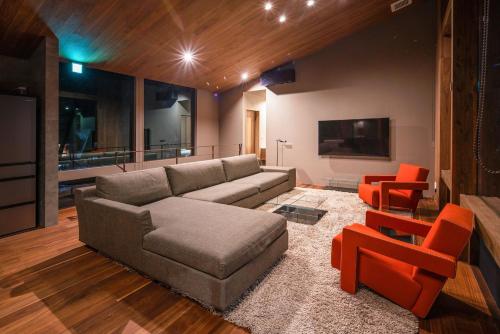 sala de estar con sofá y sillas de color naranja en Gravity by The Hakuba Collection, en Hakuba