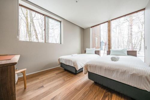 2 camas en una habitación con ventanas grandes en Gravity by The Hakuba Collection, en Hakuba