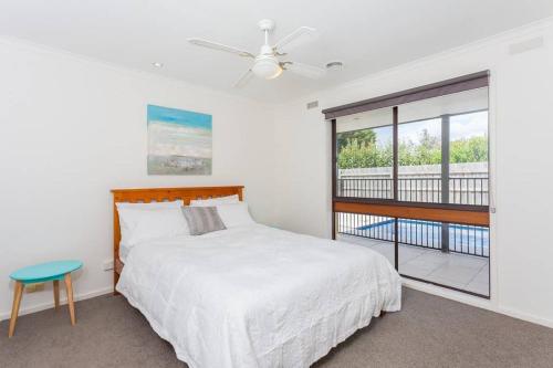 a white bedroom with a bed and a window at Charmes, paradise by the shore in Tootgarook