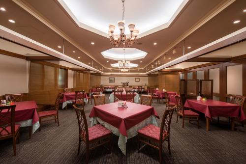 een restaurant met rode tafels en stoelen en een kroonluchter bij Grand Hotel New Oji in Tomakomai