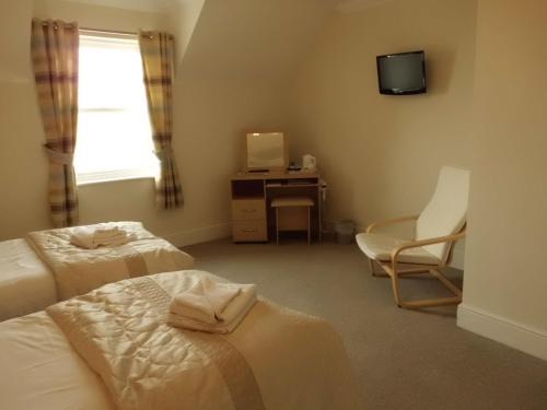 a room with two beds and a desk and a television at The Golden Lion Hotel in Maryport