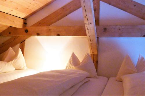 Cette chambre comprend un lit superposé avec des oreillers blancs. dans l'établissement Ferienwohnung Grischuna, à Bivio