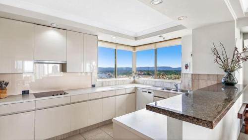 a kitchen with white cabinets and a large window at Contessa Holiday Apartments in Gold Coast