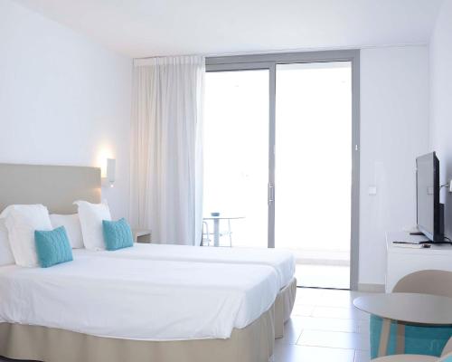a white bedroom with a large bed and a tv at Apartaments B-Llobet Sun & Confort in Ibiza Town