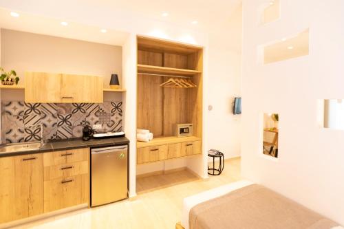 a kitchen with wooden cabinets and a bed in a room at Louis Studios Santorini in Kamari