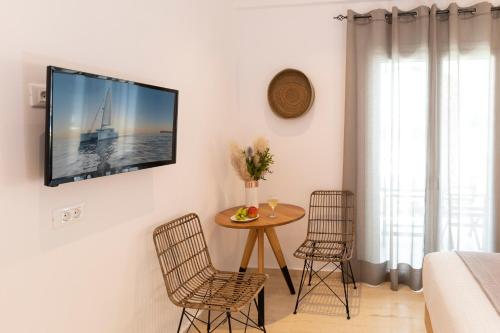 a living room with a table and a tv on the wall at Louis Studios Santorini in Kamari