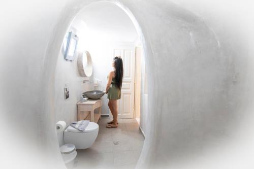 a woman standing in a bathroom with a sink at Erato Apartments in Firostefani