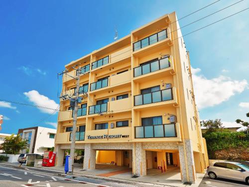 a yellow building on a street with a car in front at Terrace Resort Chatan West in Chatan